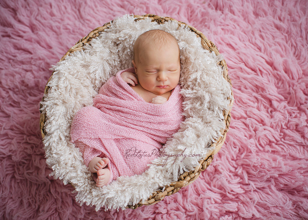 baby in a swaddle wrap and newborn basket prop
